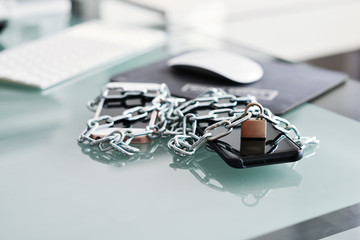 Concept of addiction to internet connection with smartphones tied with metallic chain and padlock
