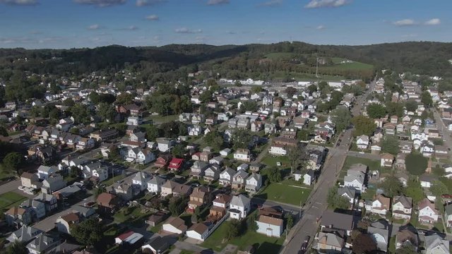 A cinematic wide orbiting aerial view of a typical western Pennsylvania residential neighborhood on a late summer day. Pittsburgh suburbs.  	