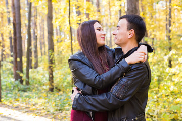 People, family and leisure concept - young couple having fun in the autumn park