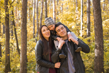 Family, fall, people concept - young family walking in park in autumn day, hugging and smile