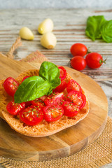 Fresh tomato bruschetta with basil on wooden background.