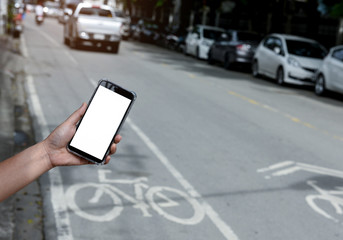 Smartphone white display in hand with blurred road background..