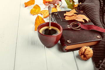 Cup coffee with book in leather binding autumn dry leaf and warm