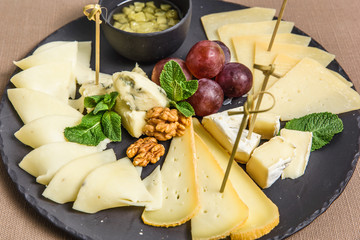 variety of cheeses on a square ceramic plate with lemon and honey nuts