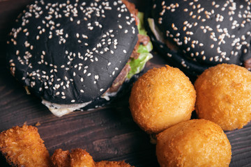 Black burger, snacks, fast food on a wooden background, top view