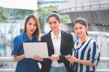 Three business woman holding laptop for online marketing team concept