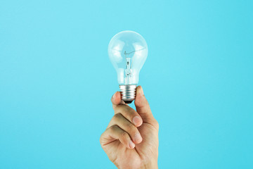 Hand holding light bulb on blue background. Concept for new ideas with innovation and creativity.