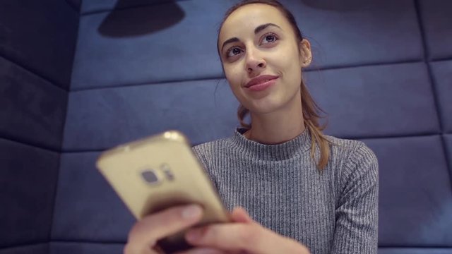 Smartphone girl using app on phone drinking coffee smiling in cafe. Beautiful young casual female professional on mobile phone.