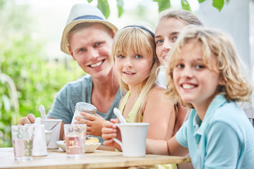 Familie sitzt entspannt am Kaffeetisch im Garten