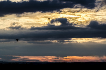 Hot air balloon flying into dramatic sunset