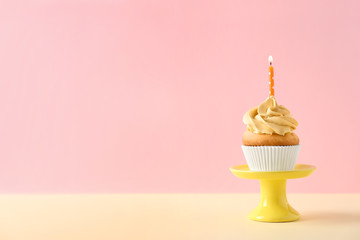 Dessert stand with delicious birthday cupcake on color background