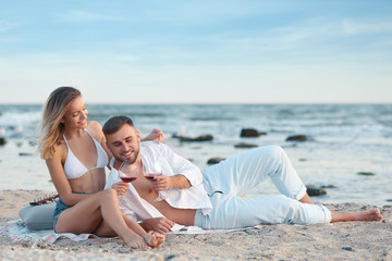 Fototapeta premium Young couple with glasses of wine on beach