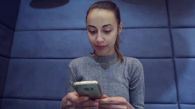 Smartphone girl using app on phone drinking coffee smiling in cafe. Beautiful young casual female professional on mobile phone.