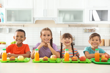 Children sitting at table and eating healthy food during break at school