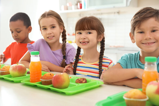Children sitting at table and eating healthy food during break at school