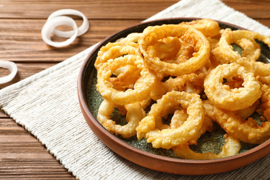Homemade crunchy fried onion rings on wooden table, closeup