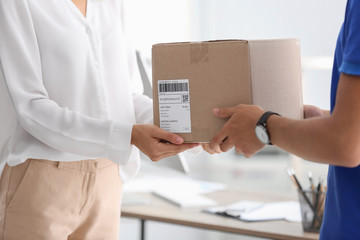 Young woman receiving parcel from courier in office