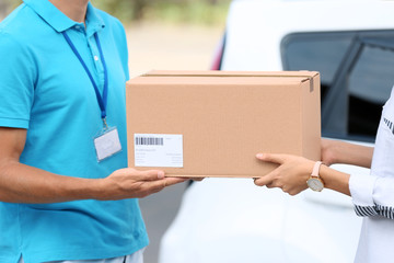 Young woman receiving parcel from courier outdoors