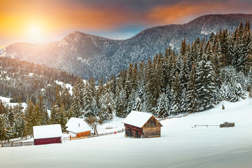 Amazing winter sunset with snowy rural wooden chalets, Transylvania, Romania