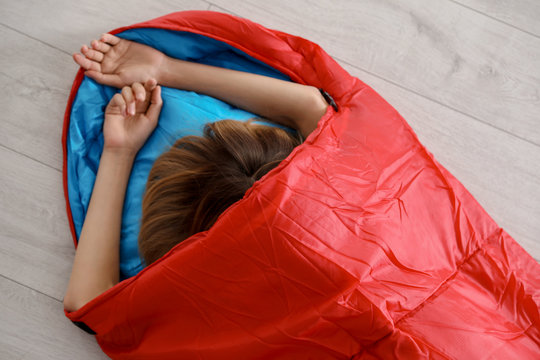 Young Woman In Comfortable Sleeping Bag On Floor, Top View