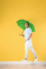 Man with green umbrella near color wall © New Africa