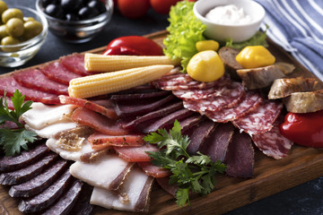 Different sausages with pickled vegetables on wooden board. Closeup
