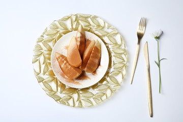 Flat lay composition with plate of sliced pears and cinnamon on white background