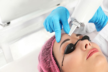 Naklejka premium Woman undergoing laser tattoo removal procedure in salon, closeup
