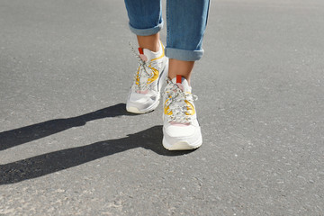 Woman in stylish sneakers walking outdoors, focus on legs