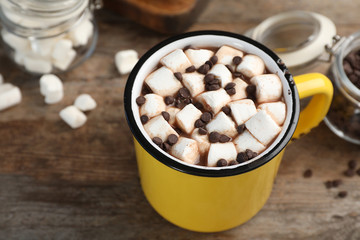 Cup of chocolate milk with marshmallows on wooden table, closeup