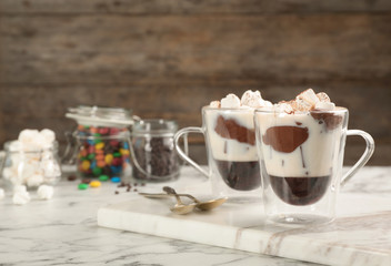 Cups of chocolate dessert with marshmallows on marble table. Space for text