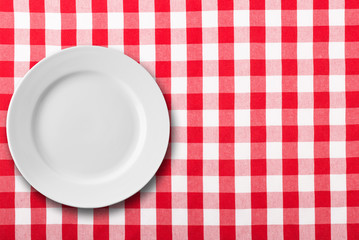 empty white plate on red checkered tablecloth