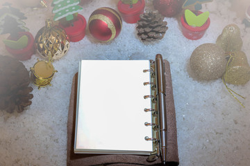 Top view image of Christmas festive decorations with empty notebook and silver pen on old wooden background. Christmas decoration Christmas items on an old wooden surface.