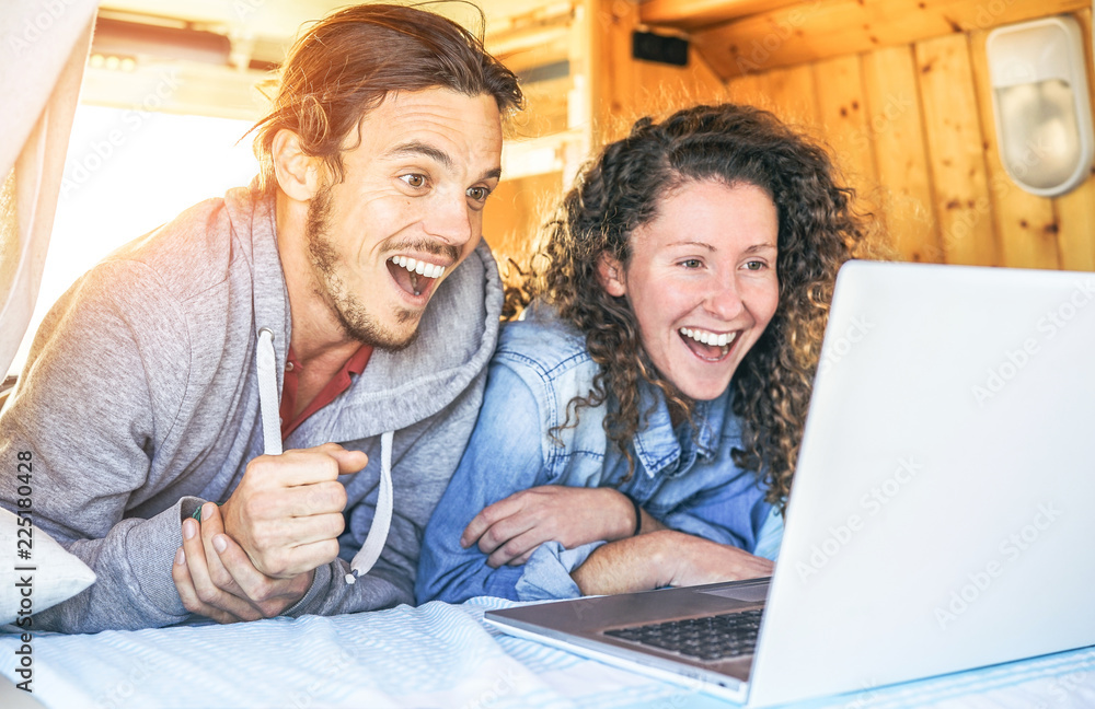 Wall mural happy man and woman watching surprised on their computer - travel couple using laptop during their j