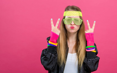 Woman in 1980's fashion giving the peace sign on a pink background