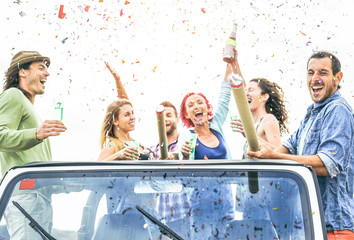 Group of happy friends making party throwing confetti on convertible jeep car - Young people...