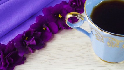 Obraz na płótnie Canvas A Cup of coffee and a violet flower on a purple background.