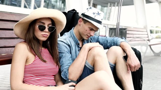 Couple At Travel. Sad Young People Waiting Flight At Airport