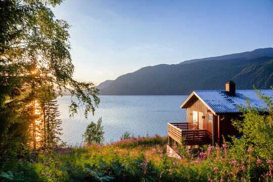 Wooden summerhouse with terrace overlooking scenic lake at sunset in Norway Scandinavia