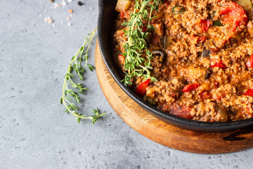 Pan of italian sauce bolognese with thyme on grey concrete background. Copy space.