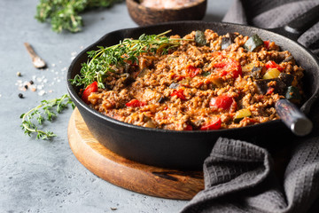 Pan of italian sauce bolognese with thyme on grey concrete background. Copy space.