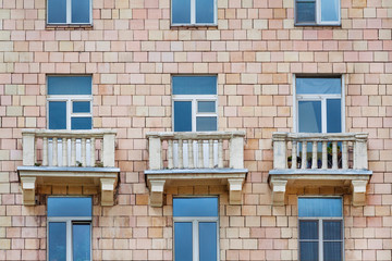 Obraz premium Front view on fragment of facade of a old brick residential house with three balconies (texture, background)