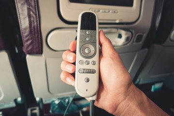 Close-Up of Male Hand is Holding Remote Electronic Device Entertainment Multimedia Control on Air Flight, Airplane Facility Service on Passenger Seat. Monitor Control inside Passengers Cabin Aircraft