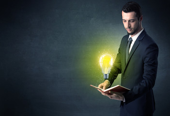 Businessman holding book with bulb.