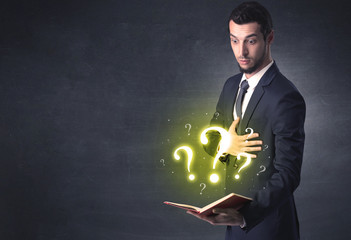 Businessman holding a book with question mark symbol.