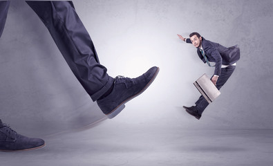 Deported from workplace, big foot kicking small businessman flying away
