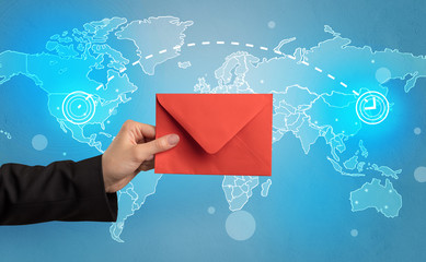Female hand holding coloured and white envelope with blue map on the background
