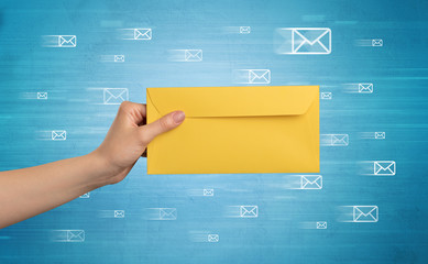 Female hand holding coloured and white envelope with blue background and message symbols around
