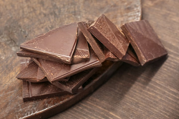 Pieces of the dark chocolate on the brown wooden retro plate 