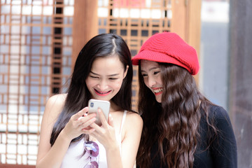 Duo asian portrait girl have playing a mobile phone and talking with fun and happiness.